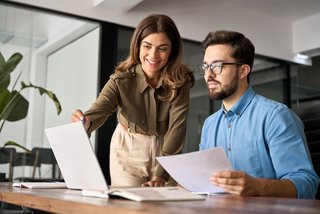 Professional happy manager explaining software helping employee at work.