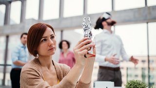 Young businesswoman or scientist with robotic hand standing in office, working. Young businesswoman or scientist with robotic hand standing in office, working.