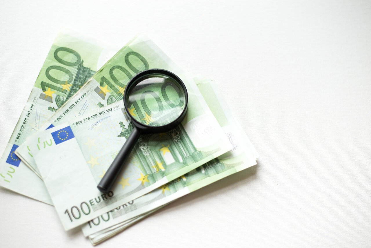 Hundred euro banknote under magnifying glass isolated on white background