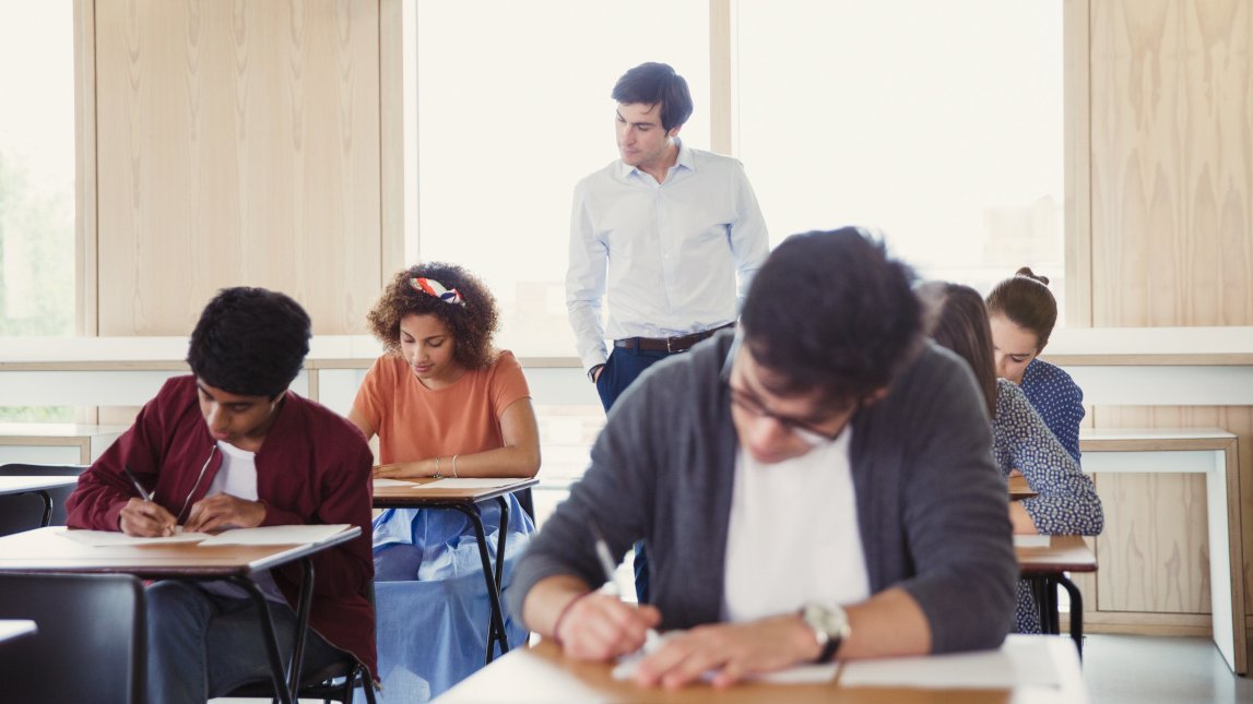 Professor beobachtet Studenten bei einem Test im Klassenzimmer