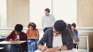 Professor beobachtet Studenten bei einem Test im Klassenzimmer