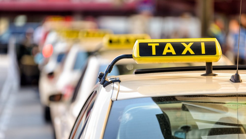 Auf dem Dach eines Taxis leuchtet ein Taxi-Schild.