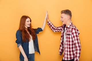 Portrait of a happy teenage couple giving high five