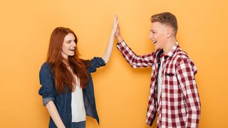 Portrait of a happy teenage couple giving high five