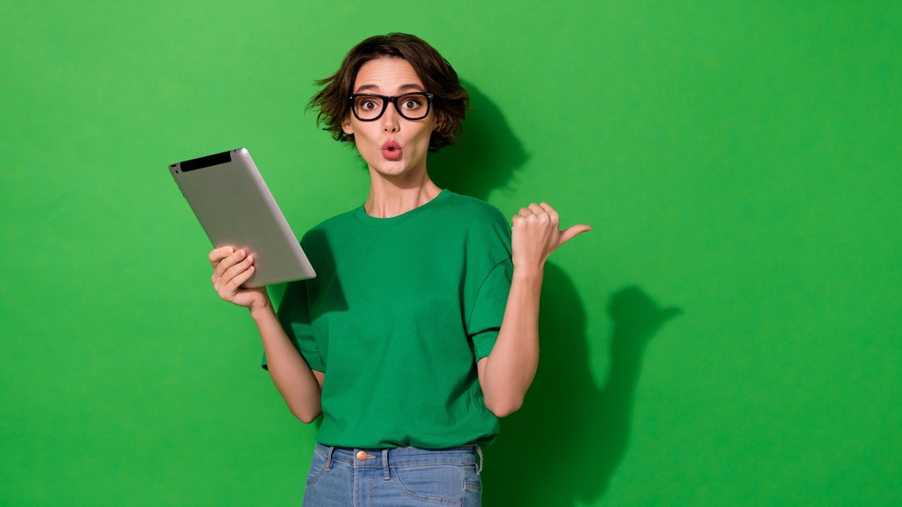Photo of charming impressed woman dressed summer t-shirt eyewear typing gadget empty space isolated green color background